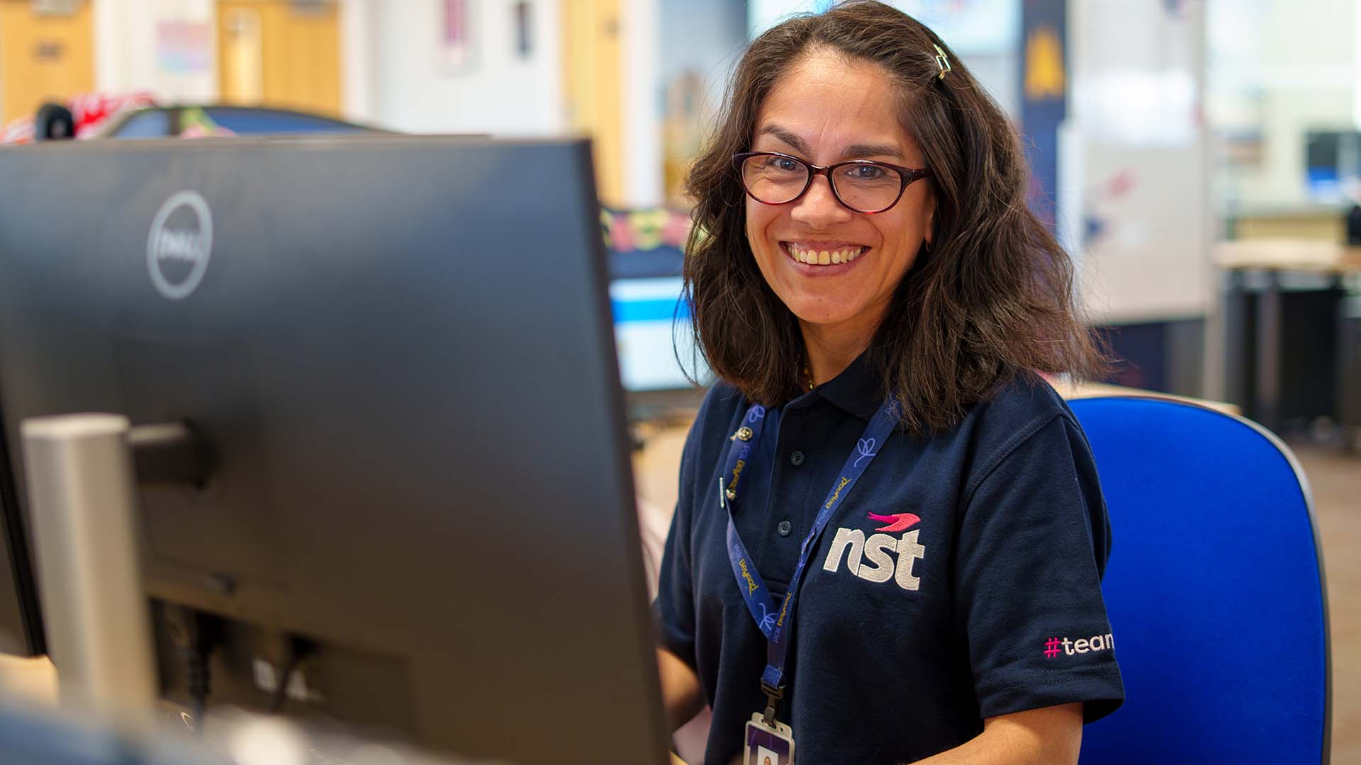 NST team member smiling at their desk